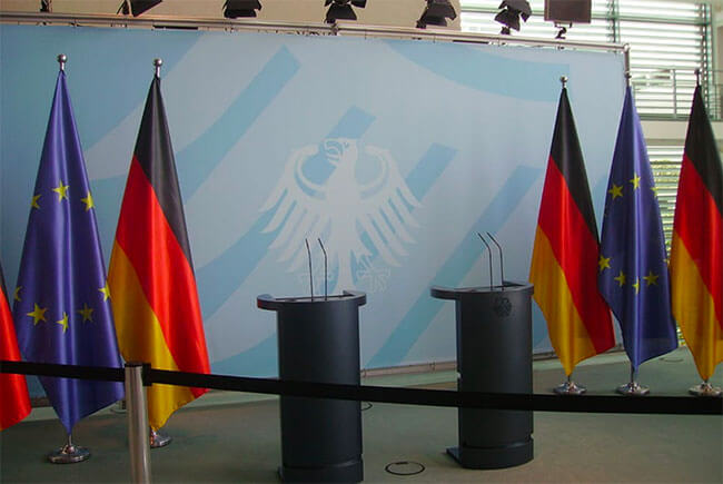 EU och tyska flaggor bredvid ett tomt podium