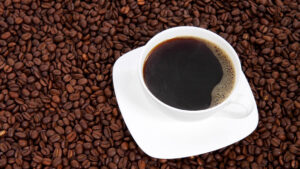 en kopp kaffe stående på kaffebönor